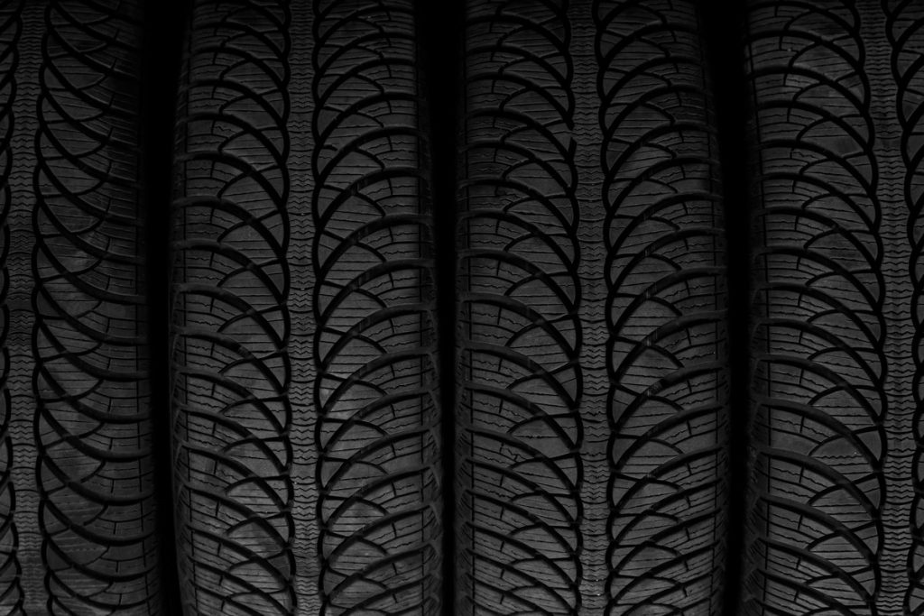 Closeup picture, four black rubber automobile tire with protector