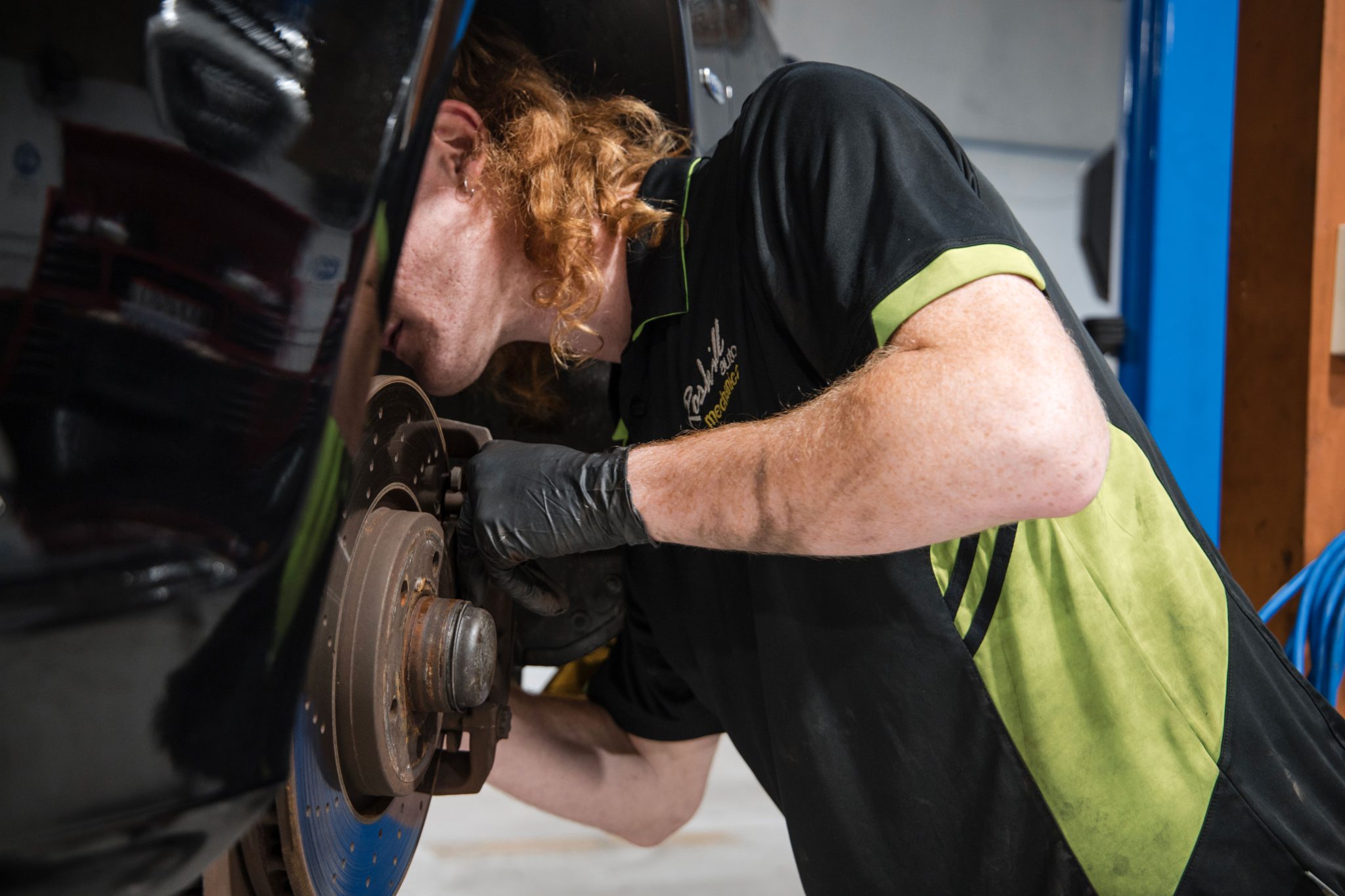 mechanic checks behind tyre area for any repairs